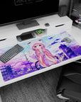 Pink-haired anime girl waving on a rooftop desk pad 40x20 inches, twin locks and bubble dots around her.