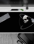 Midnight black desk pad 40x20 inches with clean white orbit lines and a tiny red eye, moody vibe.