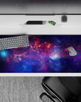 Cosmic desk pad 36x16 inches in deep violet and midnight blue with sparkly nebula pink glow.