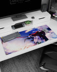 Silver-haired anime swordswoman in red-black coat on desk pad 36x16 inches, blade catching the light.