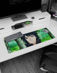 32x12 inches anime mouse pad showing Sasuke Uchiha staring ahead, dark hair sharp, blurred green backdrop.