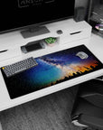 Star-filled night sky desk pad with pine silhouettes and warm amber glow on the horizon, 36x16 inches.
