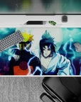 Naruto and Sasuke back to back under a moonlit sky on a 40x20 inch anime desk pad, capturing iconic tension.