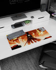 Eren Yeager from Attack on Titan stands amidst a city in flames on this 28x12 inches anime mouse pad, capturing a pivotal scene.