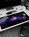 Galaxy-themed desk pad 40x20 inches with swirling violet nebula clouds, soft blue stardust, and scattered tiny stars.