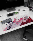 Blonde anime woman in gloves before exploding pink flowers, dramatic scene desk pad 36x16 inches.