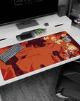 Blond scarfed anime hero tumbling with sword over ruined pillars on desk pad 40x20 inches.