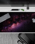 Calming night-sky desk pad 40x20 inches in inky black with purple and blush nebula hues.