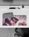 Nezuko from Demon Slayer lounges under wisteria on a 28x12 inch anime mouse pad, surrounded by blush-pink blooms.