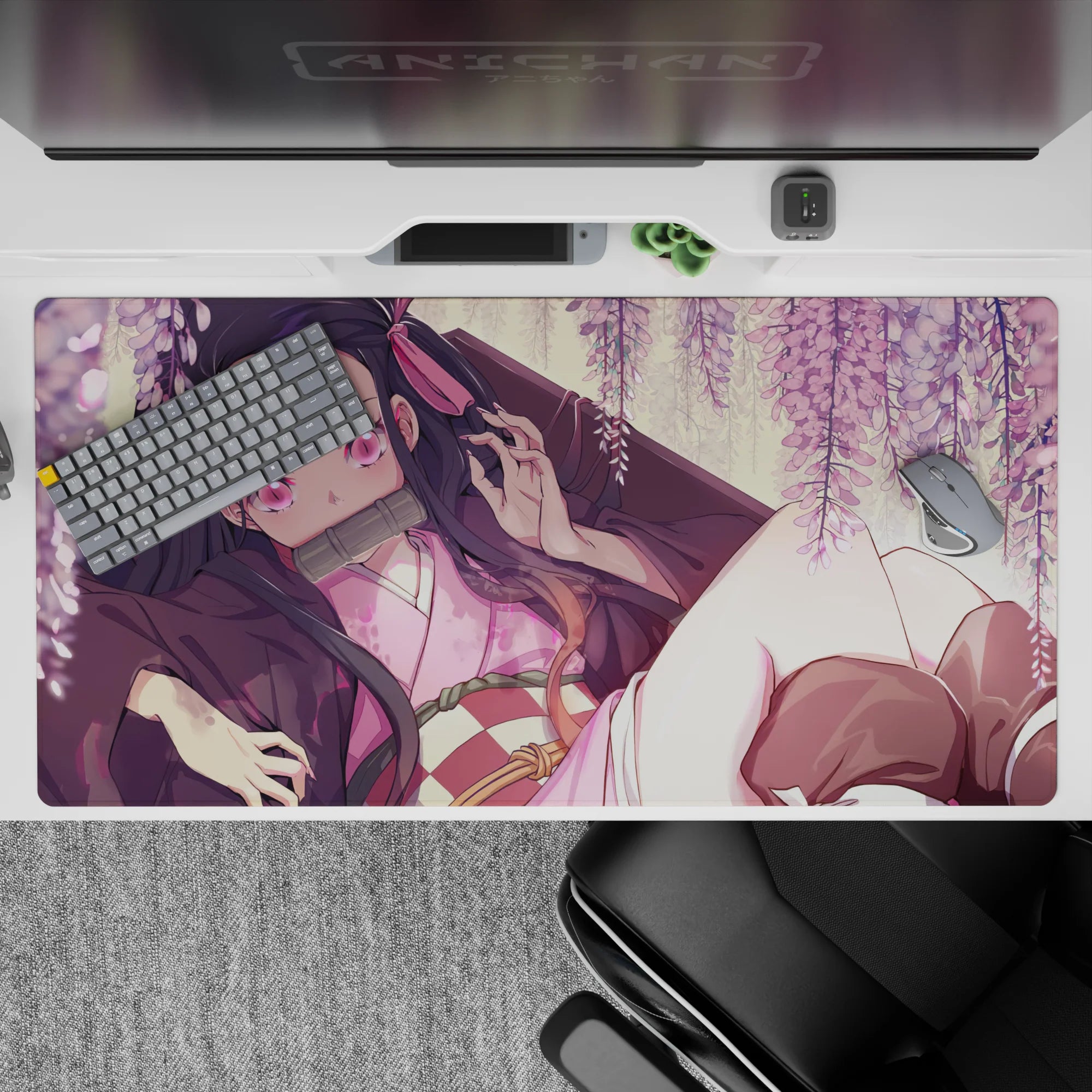 Nezuko from Demon Slayer lounges under wisteria on a 40x20 inch anime desk pad, surrounded by blush-pink blooms.