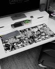 Tomoko Kuroki deadpan stare and shy slouch scene desk pad, tiny Tomokos in background, 36x16 inches.