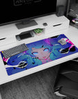 36x16 inches anime desk pad showing a blue twin-tail girl staring ahead, violet eyes and glitch splashes.