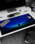 Two characters sitting close on a grassy hill under a sapphire star sky on an anime desk pad 40x20 inches.