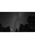 Forest silhouette under a starry Milky Way night sky desk pad, 40x20 inches.