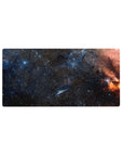 Midnight galaxy desk mouse pad 32x16 inches with swirling starry space design and orange nebula edge.