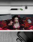 Nezuko anime desk pad 36x16 inches with fierce pink eyes and spiraling hair in a blazing red haze, perfect for any setup.
