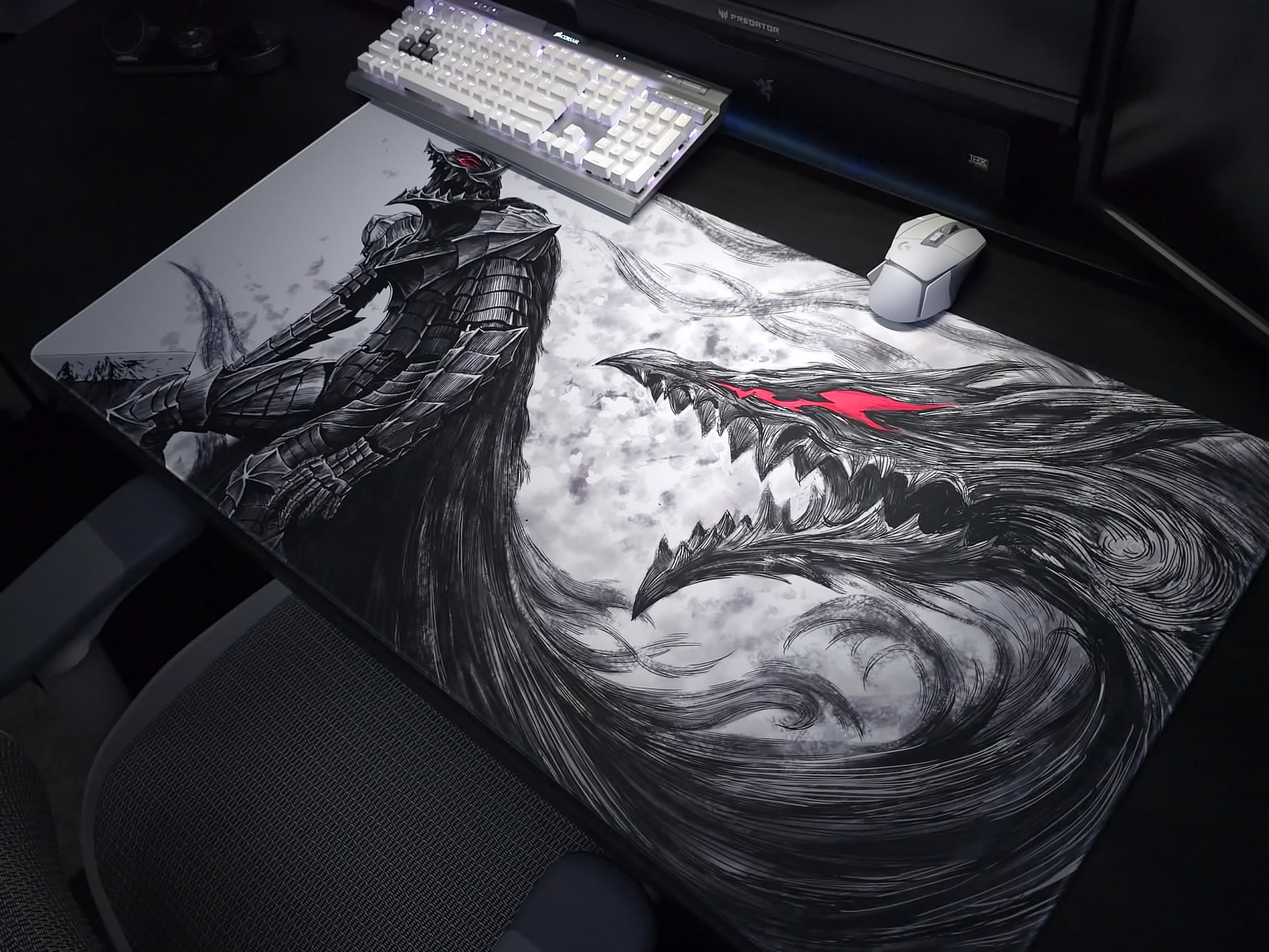 A large desk mat featuring a black and white comic-style illustration of a knight and a dragon with a red eye, shown on a desk with a keyboard, mouse, and monitor in a dim room.
