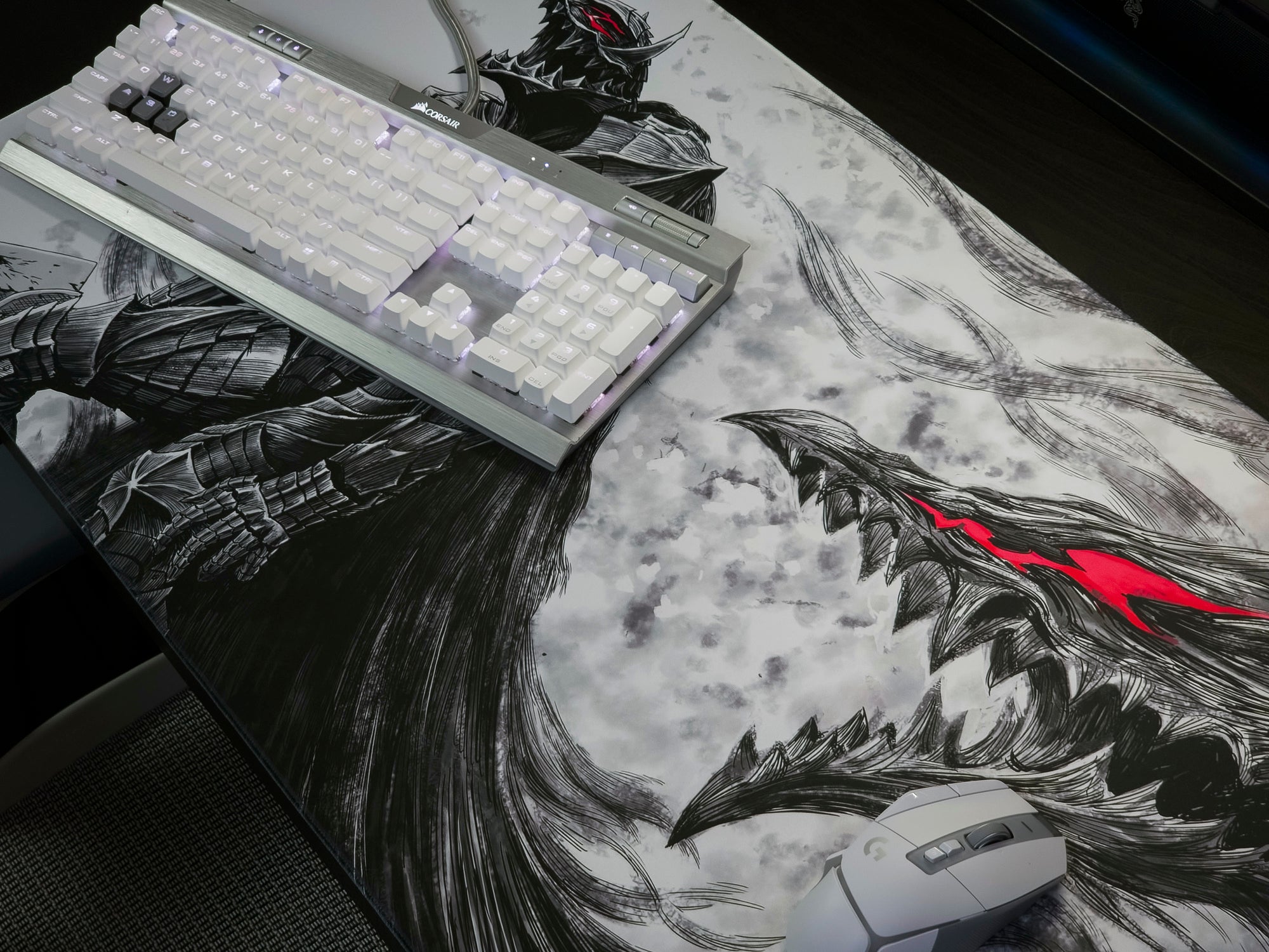 A large gaming desk mat featuring a black and white anime-style dragon illustration with a bright red accent, shown on a desk with a keyboard and mouse.